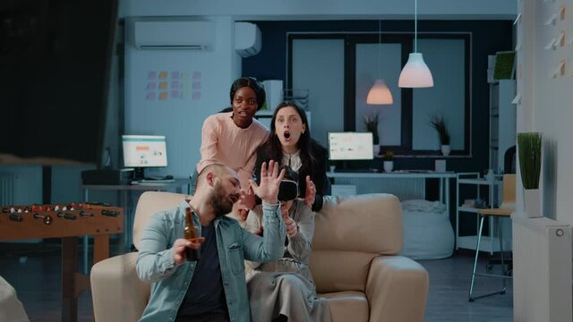 Colleagues enjoying drinks and video games on television after work. Woman playing game with joystick on console tv while wearing vr glasses and losing. Coworkers with entertainment