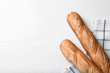 Tasty baguettes on white wooden table, flat lay. Space for text