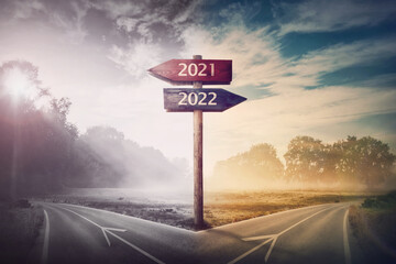 Conceptual scene choose road 2022 year or 2021. Split ways and signpost arrows showing two different courses, left and right Go ahead to the future or turn back to past. Life decision and choice - 465085256