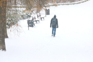 A man walks through the park on a snowy day. Out of focus, blurred background.