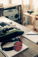 Headphones and vintage old typewriter at wooden desk table