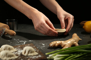 Woman making gyoza at grey table, closeup