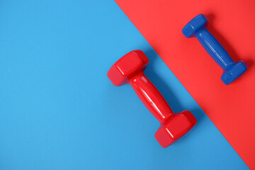 Red and blue dumbbells on an inverted diagonal background. Sport and fitness equipment, dumbbells