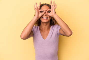 Young latin transsexual woman isolated on yellow background excited keeping ok gesture on eye.
