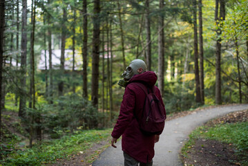 casual young man in a gas mask standing on the forest. Ecological catastrophy. Post apocalyptic...