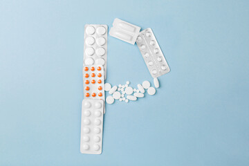 Letter P from medical pills, blisters, syringe and vaccine vial on blue background. Pharmaceutical alphabet. Complex therapy. 