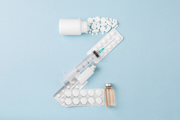 Letter Z from medical pills, blisters, syringe and vaccine vial on blue background. Pharmaceutical alphabet. Complex therapy. 