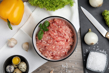 Raw chicken minced meat and ingredients on wooden table, flat lay