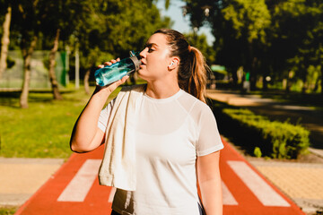 Fit sporty caucasian athlete plus-size body positive woman drinking water, feeling thirsty after...