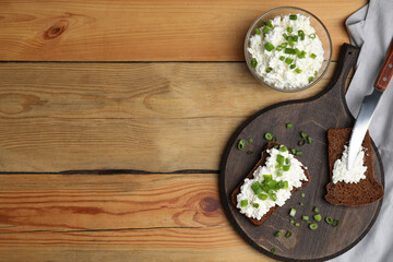Bread with cottage cheese and green onion on wooden table, flat lay. Space for text