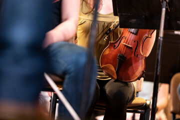 A violin or viola player sitting in a symphony orchestra during a rehearsal and waiting for the conductor to finally stop talking