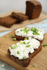 Bread with cottage cheese and green onion on table, closeup