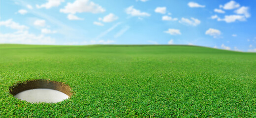 Golf hole in a golf course field. Panoramic grass landscape background with copy space. - obrazy, fototapety, plakaty