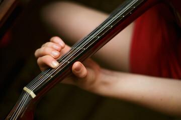 child's hand holds a guitar chord