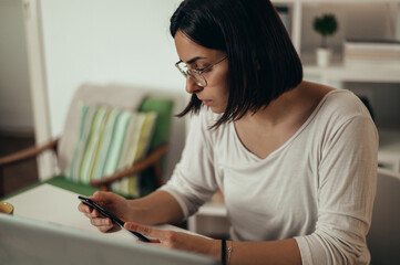 Beautiful woman using smartphone and a laptop while working from home