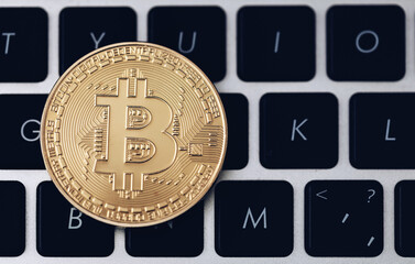 Bitcoin on compuer keyboard in background, symbol of electronic virtual money and mining cryptocurrency concept. Coin crypto currency bitcoin lies on the keyboard. Bitcoin on keyboard.
