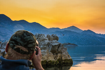 Wildlife photographer during sunset on kayak in Skadar Lake. - Powered by Adobe