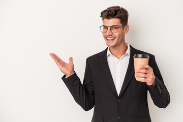 Young business caucasian man holding take away coffee isolated on white background showing a copy space on a palm and holding another hand on waist.