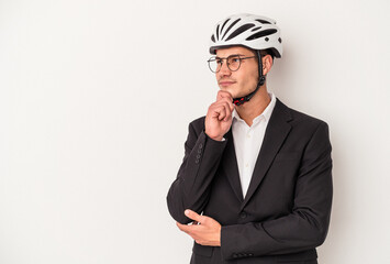 Young business caucasian man holding bike helmet isolated on white background looking sideways with doubtful and skeptical expression.