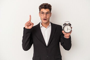 Young business caucasian man holding alarm clock isolated on white background having an idea, inspiration concept.
