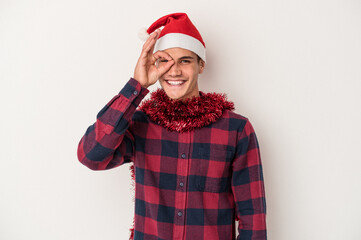 Young caucasian man celebrating Christmas isolated on white background excited keeping ok gesture on eye.