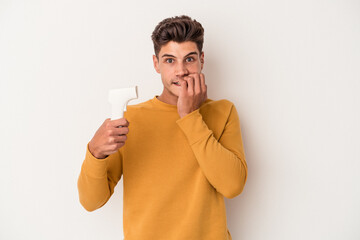 Young caucasian man holding thermometer isolated on white background biting fingernails, nervous...