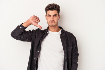 Young caucasian man isolated on white background showing a dislike gesture, thumbs down. Disagreement concept.