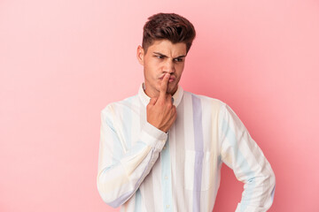 Young caucasian man isolated on pink background keeping a secret or asking for silence.