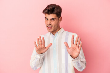 Young caucasian man isolated on pink background rejecting someone showing a gesture of disgust.