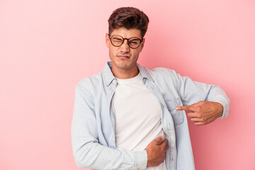 Young caucasian man isolated on pink background having a liver pain, stomach ache.
