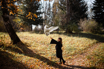 Girl in black mantile stretched out her hand to the falling owl.