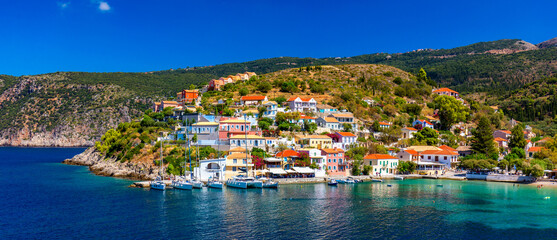 Fototapeta premium Assos village in Kefalonia, Greece. Turquoise colored bay in Mediterranean sea with beautiful colorful houses in Assos village in Kefalonia, Greece, Ionian island, Cephalonia, Assos village.