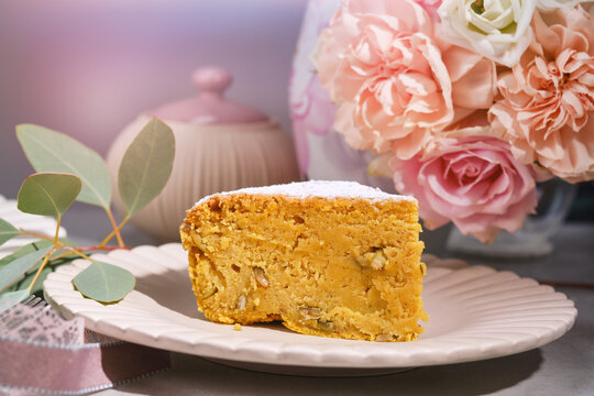 Muffin or bundt cake decorated icing sugar on the plate against vase with white and pink flowers. . Christmas Stollen traditional European festive dessert. 