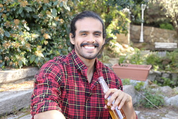 Bearded man sitting on staircase enjoying a beer