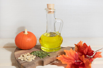 Pumpkin seed oil in a glass jug on wooden background, soft focus&