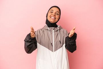 Young Arab woman with sport burqa isolated on pink background feels confident giving a hug to the...