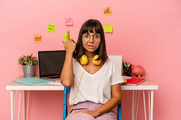 Young mixed race woman preparing a exam in the room listening to music isolated on pink background showing a disappointment gesture with forefinger.