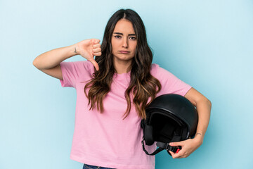 Young caucasian woman holding a motor bike helmet isolated on blue background showing a dislike...
