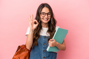 Young caucasian student woman isolated on pink background cheerful and confident showing ok gesture. - obrazy, fototapety, plakaty
