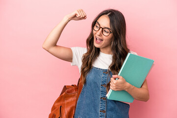Young caucasian student woman isolated on pink background raising fist after a victory, winner...