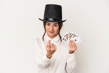 Young magician woman holding a wand isolated on white background pointing with finger at you as if inviting come closer.