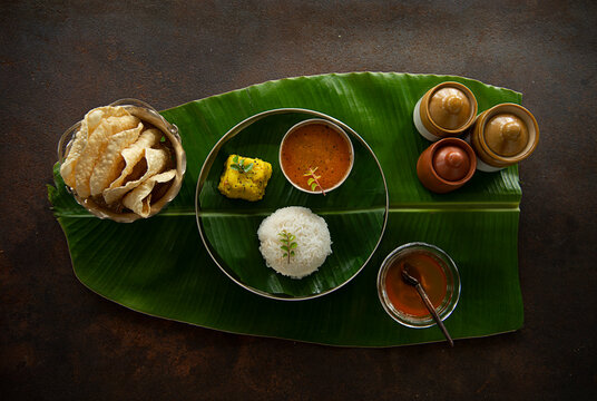 Rasam and rice served with papad and ghee 