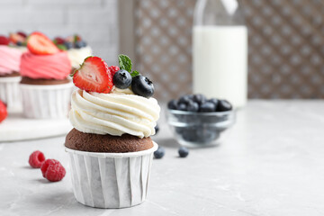 Sweet cupcake with fresh berries on light marble table. Space for text