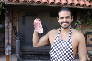Muscular shirtless man with an apron holding steak
