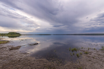 Evening landscape on the lake in early spring. The dramatic sky is reflected in the water.
