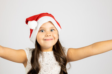 close-up portrait of happy, cute girl in Santa Claus hat taking selfie and hugging camera with hands, isolated on white background, concept of joy New Year holidays. 