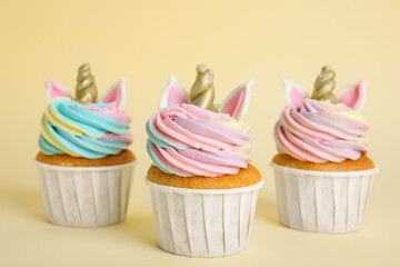 Cute sweet unicorn cupcakes on beige background