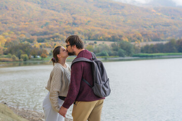 Couple in love kissing outdoors in autumn in the forest by the lake
