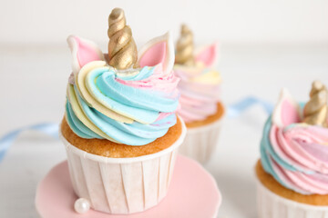 Plate with cute sweet unicorn cupcake on table, closeup
