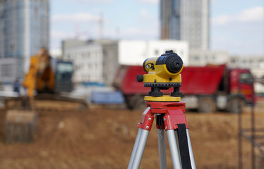 Photo of a level at the construction site of multi-storey buildings with a yellow excavator and an red truck on the street in the city